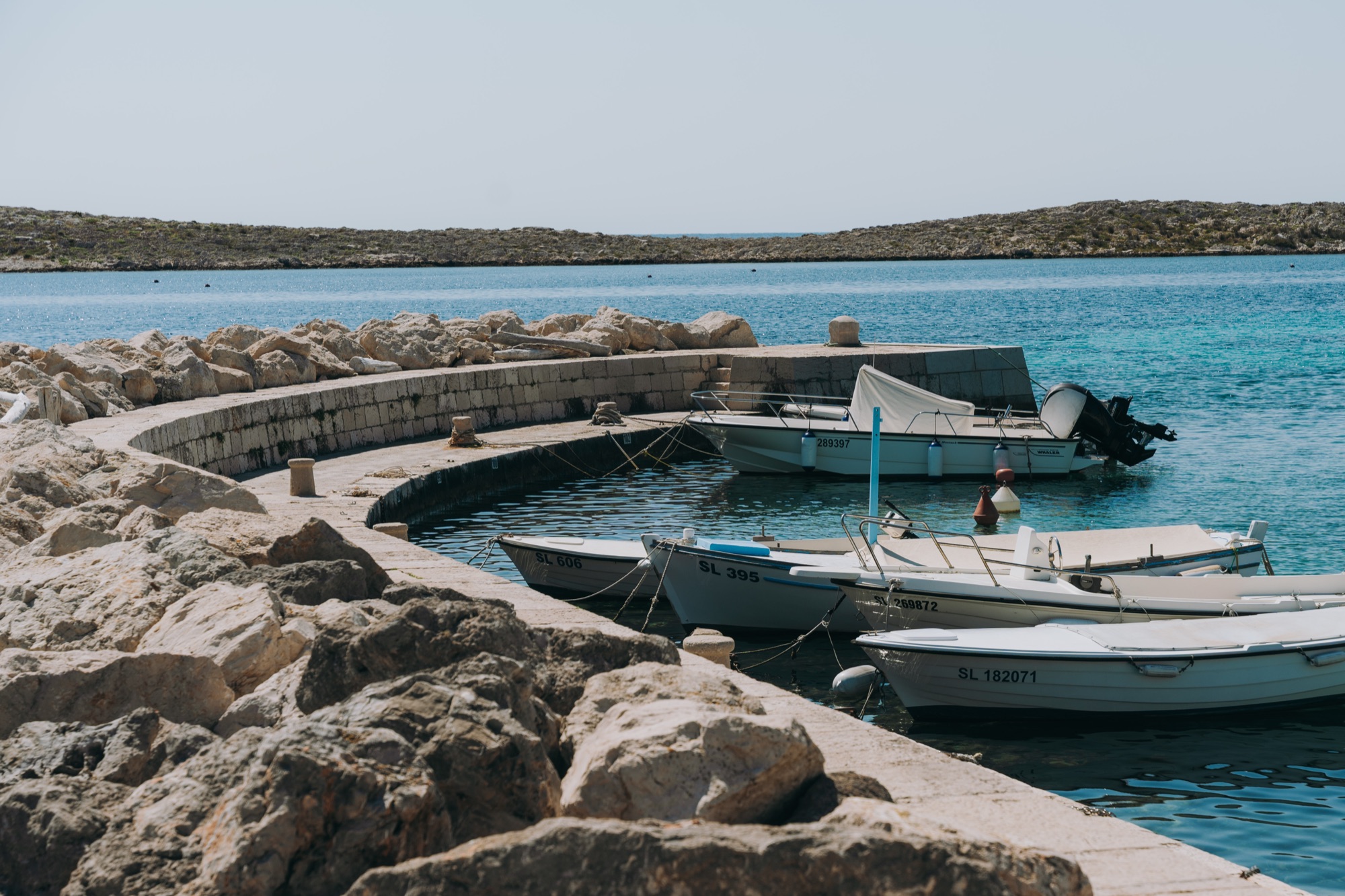 Fishing boats moored behind the stone breakwater of Premuda's old harbour